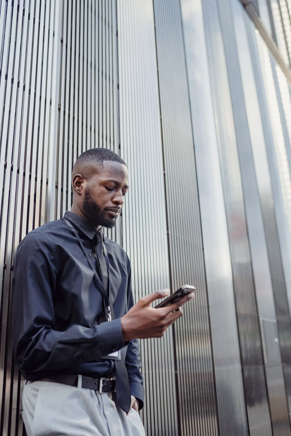 A salesperson in business dress working on a phone outside an office building.